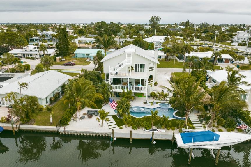A custom home by Eason in Florida with a boat dock surrounded by palm trees, showcasing a tropical waterfront setting.