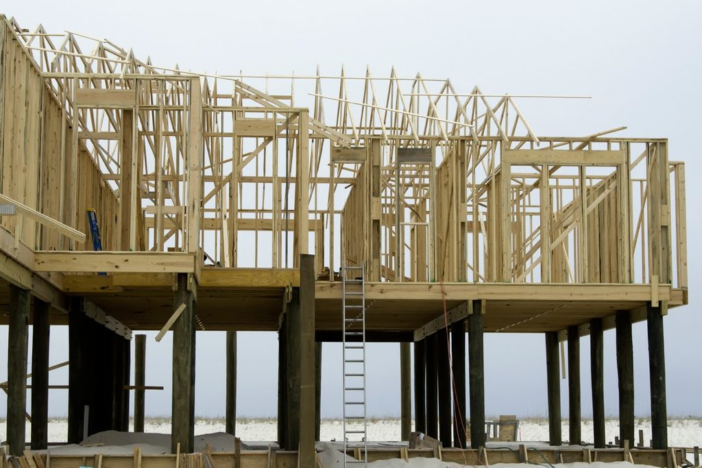 A custom home under construction on a Florida barrier island, with beach and ocean visible in the background.